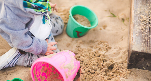 Kind beim Spielen im Sandkasten – hier können Würmer lauern.