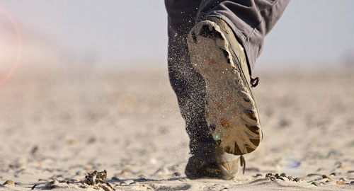 Mit Schuhen im Sand - hier könne sich Wurmeier an den Schuhen festsetzen.